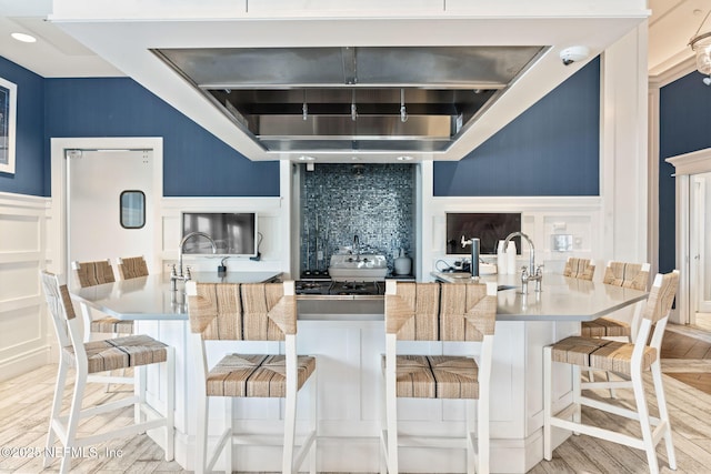 kitchen featuring backsplash, sink, a breakfast bar, and light wood-type flooring