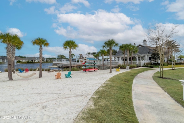 view of property's community featuring a playground, a water view, and a lawn