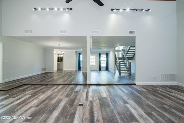 unfurnished living room featuring ceiling fan with notable chandelier, crown molding, and dark hardwood / wood-style floors