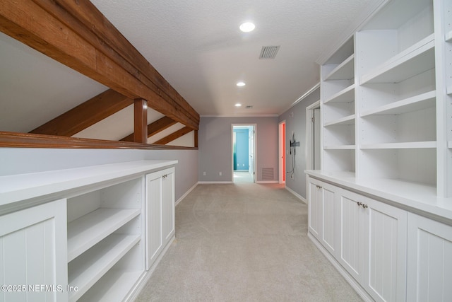 corridor featuring light colored carpet, crown molding, and a textured ceiling