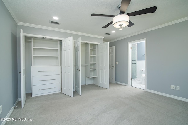 unfurnished bedroom featuring a textured ceiling, ceiling fan, ornamental molding, ensuite bath, and light colored carpet