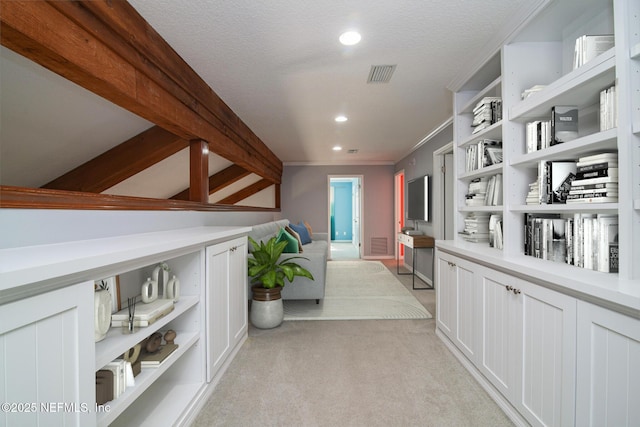 hall featuring a textured ceiling, crown molding, and light colored carpet