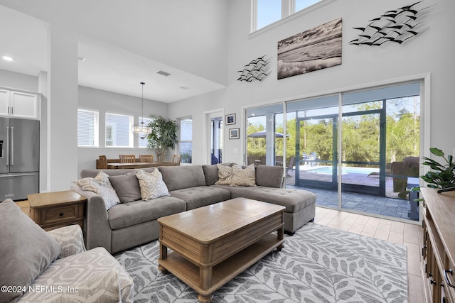 living room with a towering ceiling, a wealth of natural light, and a notable chandelier