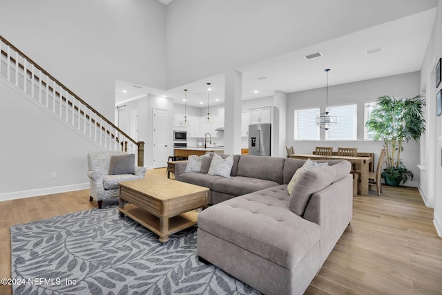 living room with light wood-type flooring, sink, and a chandelier