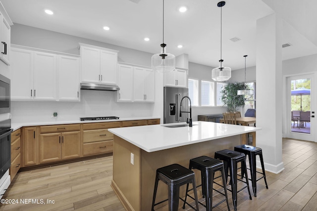 kitchen with white cabinetry, a healthy amount of sunlight, high end refrigerator, pendant lighting, and a kitchen island with sink