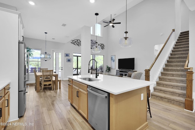 kitchen with ceiling fan, sink, a kitchen island with sink, appliances with stainless steel finishes, and light wood-type flooring