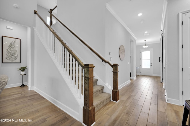 foyer entrance featuring crown molding and light hardwood / wood-style floors