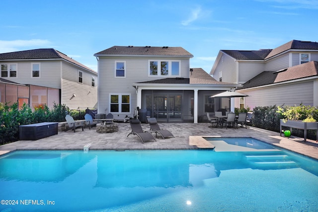 rear view of property with a fire pit, a sunroom, and a patio