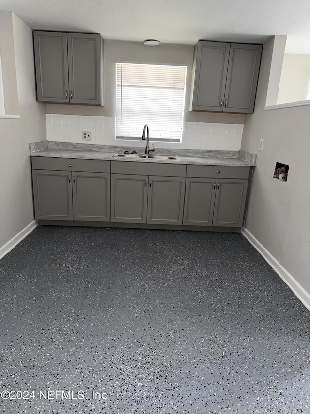 kitchen with gray cabinetry, sink, and tasteful backsplash