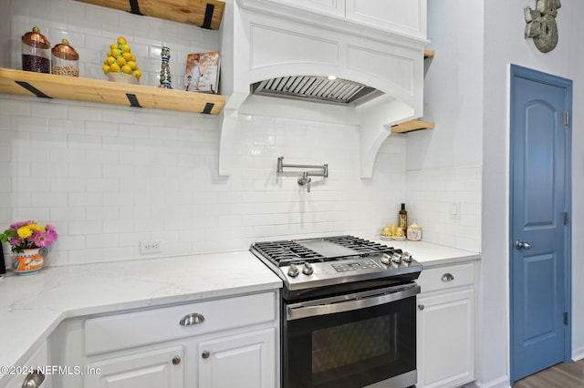 kitchen featuring light stone countertops, gas range, backsplash, and white cabinets