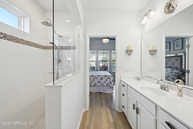 bathroom with tiled shower, wood-type flooring, and vanity