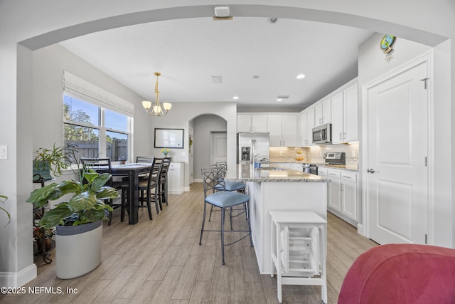 kitchen featuring white cabinets, sink, hanging light fixtures, an island with sink, and appliances with stainless steel finishes