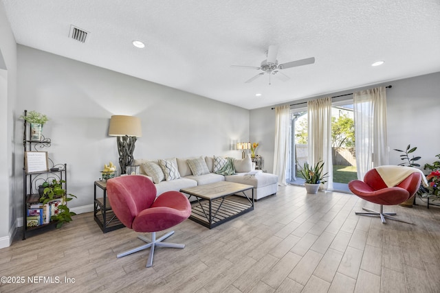 living room with ceiling fan and a textured ceiling