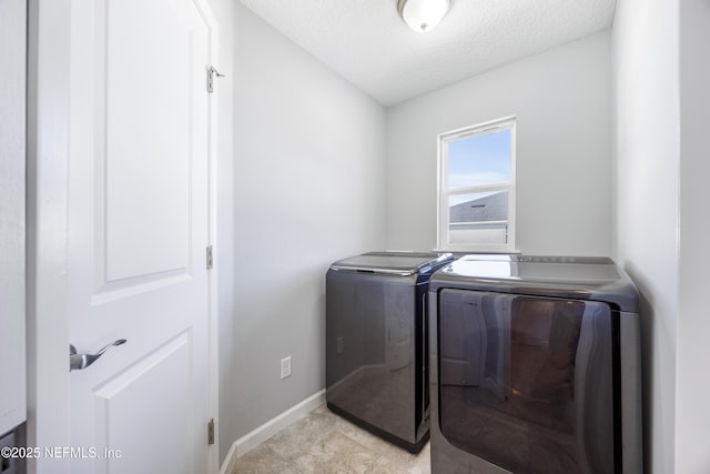 clothes washing area with washing machine and dryer and a textured ceiling