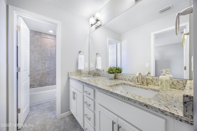 bathroom with vanity, a textured ceiling, and tiled shower / bath combo