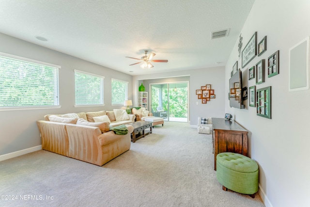 living room with ceiling fan, carpet floors, and a textured ceiling