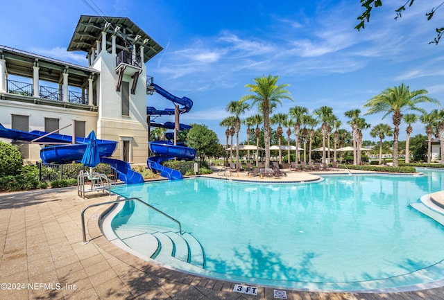 view of swimming pool with a water slide and a patio