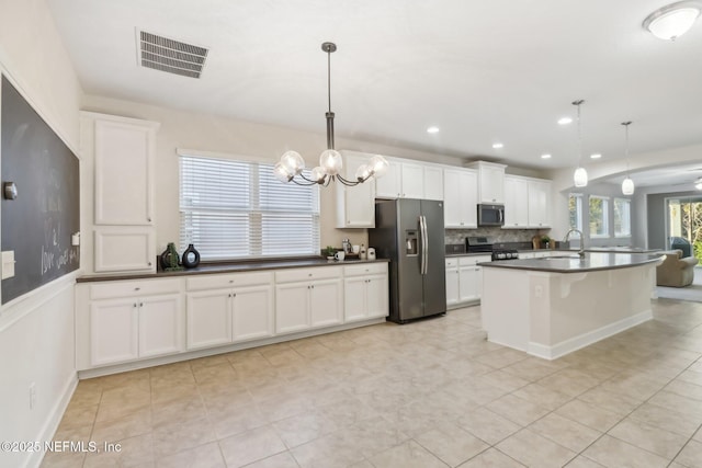 kitchen featuring white cabinets, pendant lighting, an island with sink, and stainless steel appliances