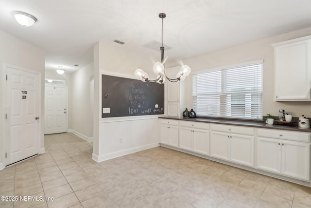 kitchen with white cabinets, light tile patterned floors, decorative light fixtures, and an inviting chandelier