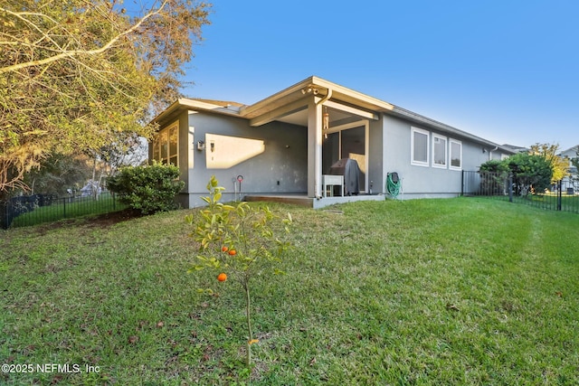 rear view of property with a lawn and a sunroom