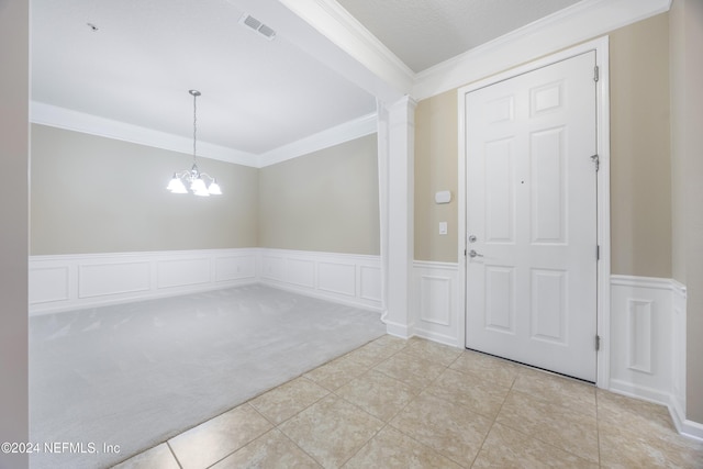 foyer entrance featuring a notable chandelier, ornate columns, crown molding, and light carpet