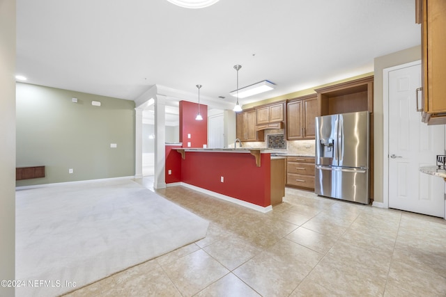 kitchen with stainless steel fridge, backsplash, pendant lighting, light tile patterned floors, and a breakfast bar area