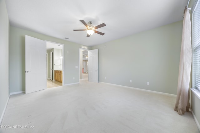 unfurnished bedroom featuring ceiling fan, ensuite bathroom, and light carpet