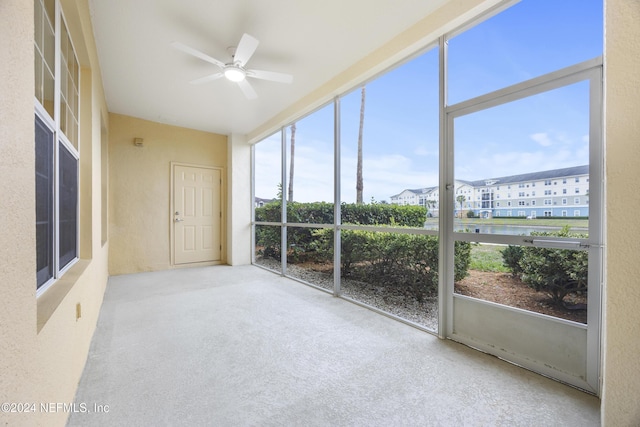 unfurnished sunroom with ceiling fan and a water view