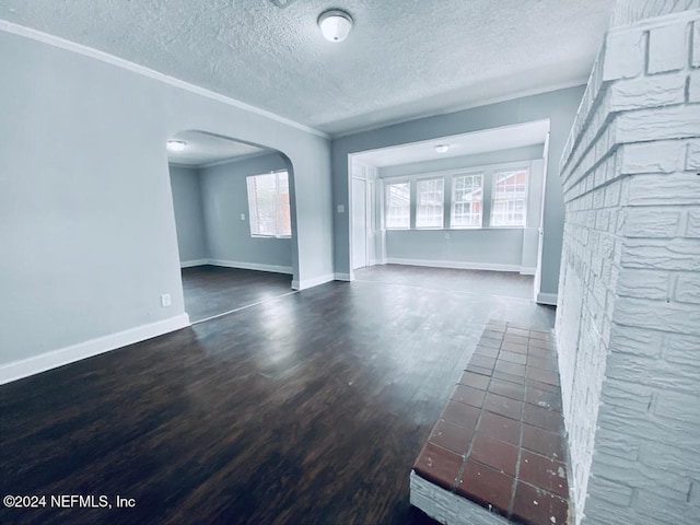 unfurnished living room featuring dark hardwood / wood-style flooring, a textured ceiling, and ornamental molding