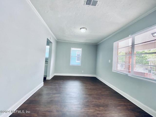 spare room with a textured ceiling, crown molding, and dark wood-type flooring