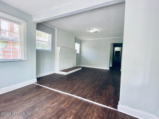 unfurnished living room featuring a fireplace, a textured ceiling, and dark hardwood / wood-style flooring