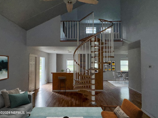 staircase featuring hardwood / wood-style flooring, a healthy amount of sunlight, and high vaulted ceiling