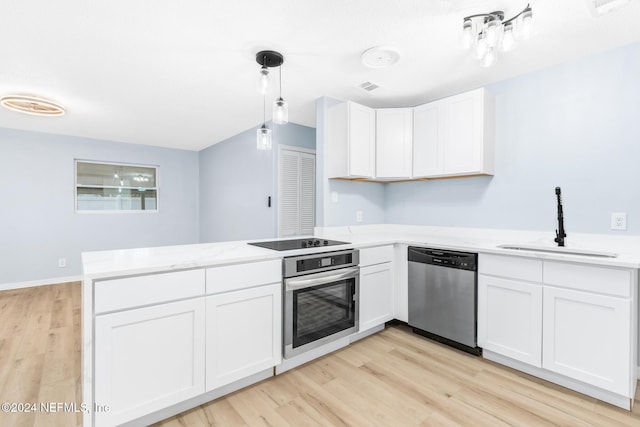 kitchen with kitchen peninsula, appliances with stainless steel finishes, sink, pendant lighting, and white cabinetry