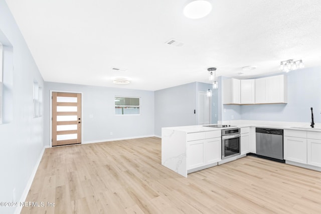 kitchen featuring kitchen peninsula, white cabinets, stainless steel appliances, and decorative light fixtures