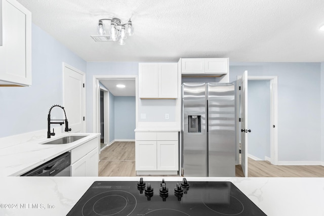 kitchen featuring white cabinets, sink, light stone countertops, a textured ceiling, and appliances with stainless steel finishes