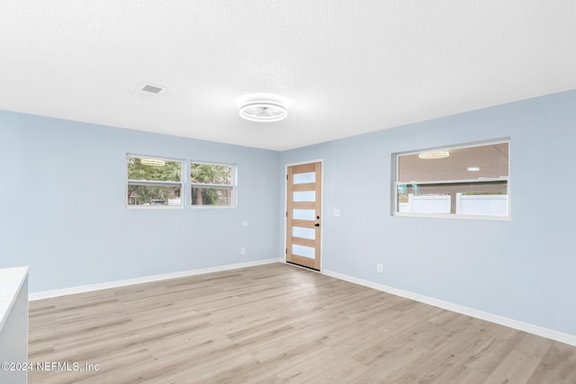 empty room featuring a textured ceiling and light wood-type flooring