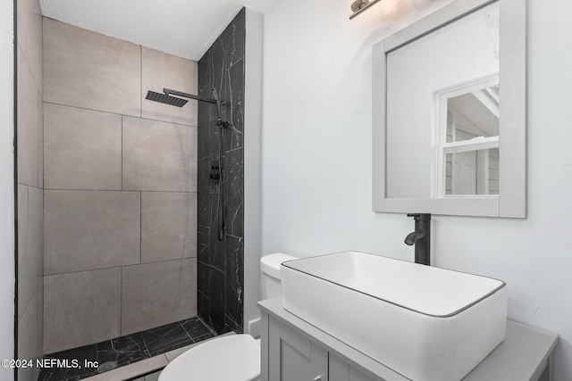 bathroom featuring tiled shower, vanity, and toilet