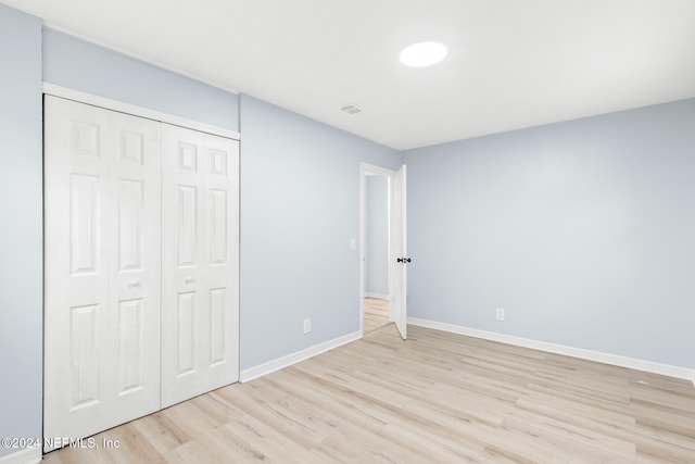 unfurnished bedroom featuring light wood-type flooring and a closet