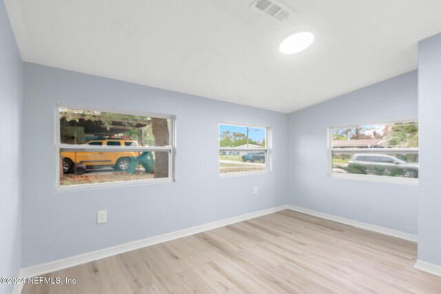 spare room with light hardwood / wood-style floors and vaulted ceiling