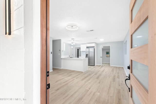 entryway with a textured ceiling and light hardwood / wood-style flooring