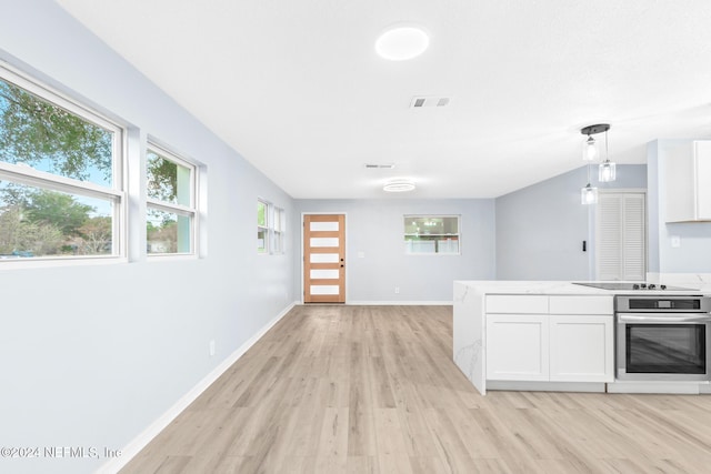 kitchen featuring white cabinets, light wood-type flooring, decorative light fixtures, and stainless steel oven