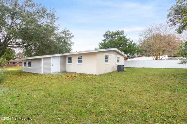 rear view of house with a lawn and central AC