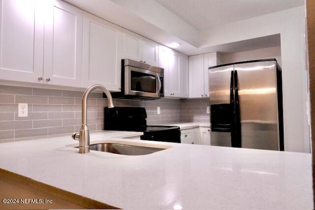 kitchen with white cabinetry, stainless steel appliances, and tasteful backsplash