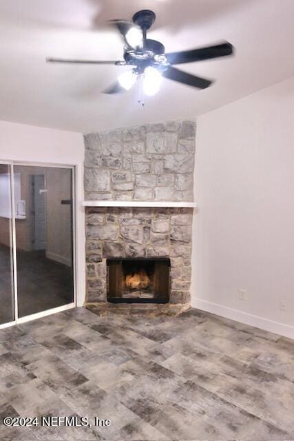 unfurnished living room with ceiling fan and a stone fireplace