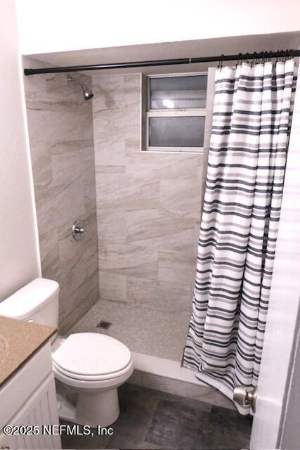 bathroom featuring curtained shower, vanity, and toilet