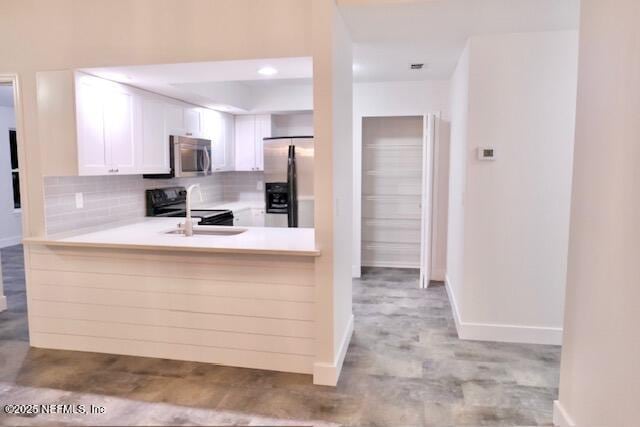 kitchen featuring white cabinets, appliances with stainless steel finishes, backsplash, and kitchen peninsula