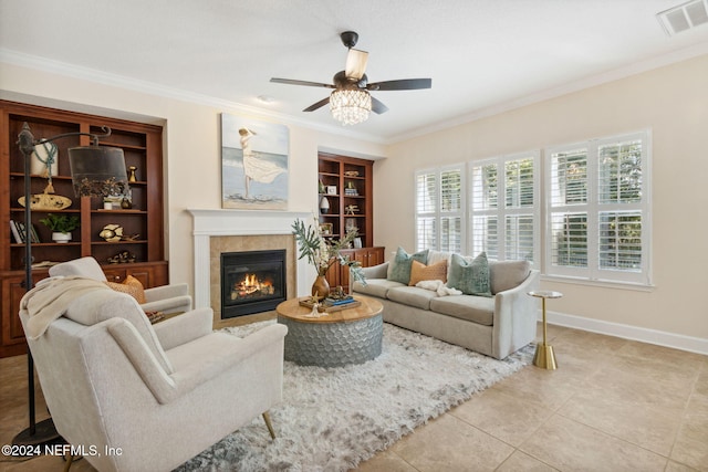 tiled living room with ceiling fan, crown molding, built in features, and a tile fireplace