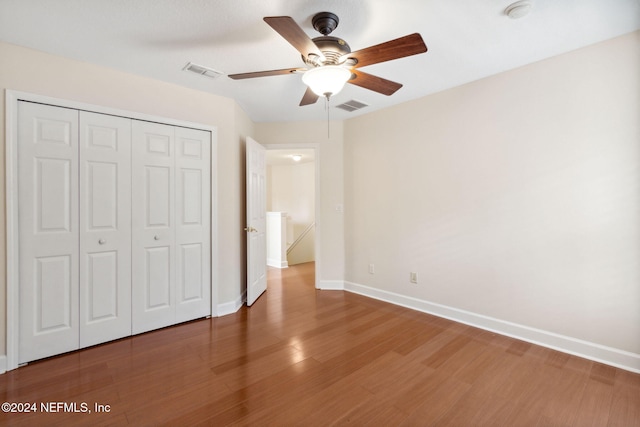 unfurnished bedroom with ceiling fan, a closet, and hardwood / wood-style floors