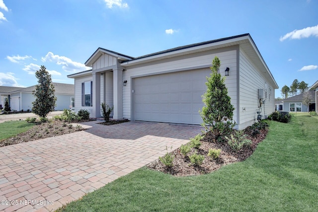 single story home featuring an attached garage, board and batten siding, decorative driveway, and a front yard