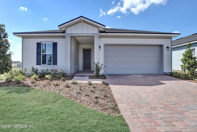 ranch-style home featuring board and batten siding, a front yard, decorative driveway, and an attached garage